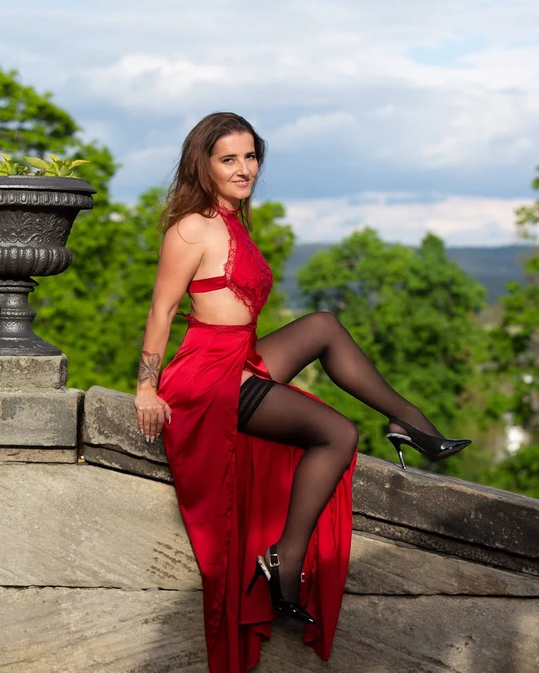 Miss Novembre 2026 con abito rosso e autoreggenti nere su una balaustra